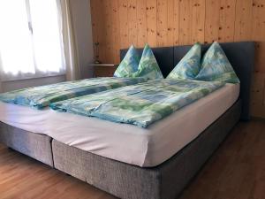 een groot bed met blauwe en groene kussens erop bij Post Hardermannli in Interlaken