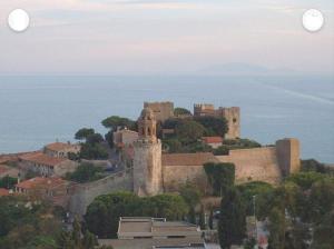 a castle on top of a hill next to the ocean at Casale nel Borgo in Castiglione della Pescaia