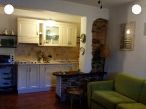 a kitchen with white cabinets and a green couch at Casale nel Borgo in Castiglione della Pescaia