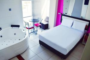 Hotel Colors Canada في ليما: غرفة نوم مع سرير وحوض استحمام وطاولة