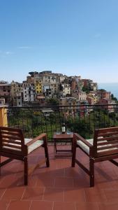 zwei Bänke und ein Tisch auf einem Balkon mit einer Stadt in der Unterkunft Cecio 5 Terre Rooms in Corniglia