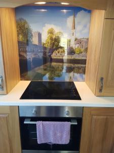 a kitchen with a painting on the wall above a stove at Ferns Holiday Let in Glenarm