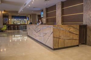 a bar in a hotel lobby with a marble wall at Hotel Golden Tulip Varna in Varna City