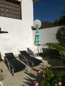 2 sillas y una sombrilla en el patio en Casa El Pino, en Mogán