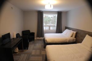 a hotel room with two beds and a window at Auberge Valcartier - Par Aneyro in Saint-Gabriel-De-Valcartier