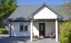 a small white house with a black door at dom do wynajecia oaza in Leszyce