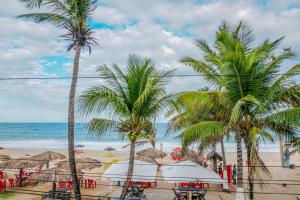 a beach with palm trees and tables and the ocean at Pousada Parador 081 in Porto De Galinhas