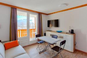 a living room with a table and a kitchen with a window at Residence Les Bergers - maeva Home in L'Alpe-d'Huez