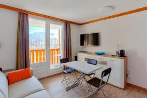 ein Wohnzimmer mit einem Tisch und eine Küche mit einem Fenster in der Unterkunft Residence Les Bergers - maeva Home in L'Alpe-d'Huez