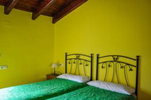 two beds in a room with yellow walls at Las Casitas de los Mata in Landete