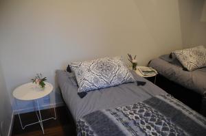 ÅsaにあるSurfers Guesthouseのベッド2台、テーブル(ベッドスカート付)が備わる小さな客室です。