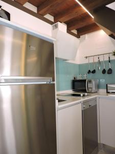 a kitchen with white cabinets and a stainless steel refrigerator at El Ático del Nuncio in Toledo