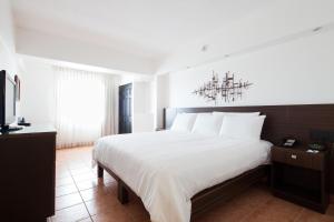 a bedroom with a large white bed and a chandelier at Hotel Presidente in San José