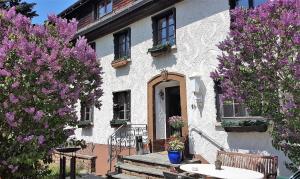 biały budynek z fioletowymi kwitnącymi drzewami przed nim w obiekcie Hotel Das Landhaus w mieście Höchenschwand