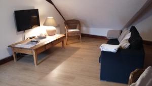 uma sala de estar com um sofá, uma mesa e uma televisão em Gite En Alsace em Rouffach