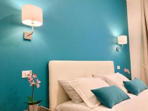Un dormitorio con una pared azul y una cama con almohadas en Cavallotti 21 en La Spezia