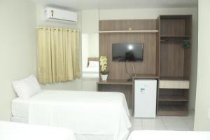 a hotel room with a bed and a tv and a tv stand at Hotel Acai in Itaituba