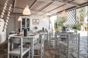 ein Restaurant mit weißen Tischen, Stühlen und Fenstern in der Unterkunft Macondo B&B in San Felice Circeo