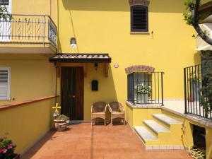 een geel huis met twee stoelen en een deur bij Camere e Casa Vacanze in Misano Adriatico