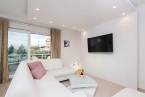 a white living room with a white couch and a tv at The Adriatic Pearl Split in Podstrana