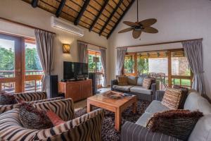 a living room with couches and a flat screen tv at Kruger Park Lodge Unit No. 277 in Hazyview