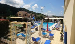 a swimming pool with blue chairs and umbrellas at Christakis in Sidari