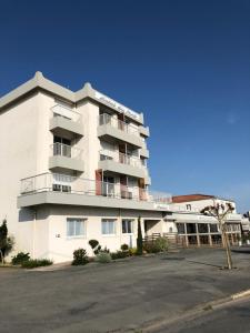 een groot wit gebouw met balkons in een straat bij Hôtel du port in LʼAiguillon-sur-Mer