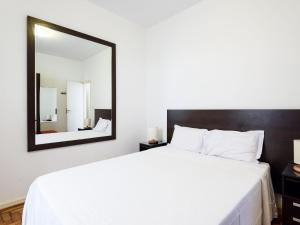 1 dormitorio con 1 cama blanca grande y espejo en Amplo 3Qtos a 600m da Praia de Ipanema | BC 33/502, en Río de Janeiro