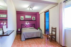 una camera con un letto e una parete con accento viola di Hostal Jentoft a Siviglia