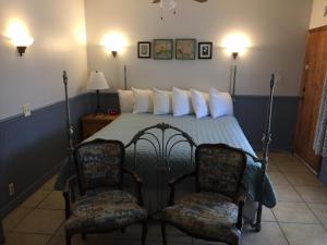 ein Schlafzimmer mit einem Bett mit zwei Stühlen in der Unterkunft Catalina Island Seacrest Inn in Avalon