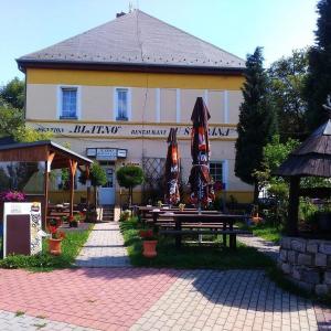 a building with tables and umbrellas in front of it at Penzion Blatno in Blatno