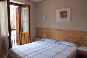 a bedroom with a white bed and a window at Pensión Lagunak in Zarautz