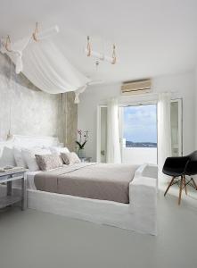 Un dormitorio blanco con una cama grande y una ventana en Milos Hotel, en Adamas