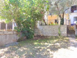 a stone wall and a tree in front of a building at Guest House Jelena in Budva