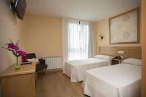 a hotel room with two beds and a window at Hotel Novoa in Sarria