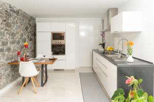 een keuken met een tafel en een stenen muur bij BHF Residences Ying Yang in Calheta