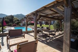 a wooden pergola with tables and chairs next to a pool at Casa Eva Maria in Patrimonio