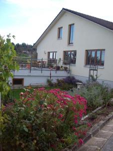 uma casa branca com flores à frente em Ferienwohnung Haus Hollerbusch em Zwiesel