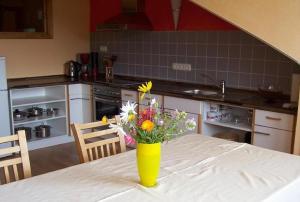 a yellow vase with flowers on a table in a kitchen at Ferienwohnung Haus Hollerbusch in Zwiesel