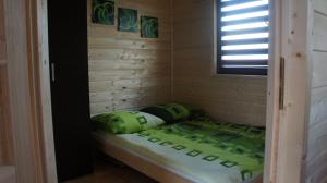 Cama pequeña en habitación de madera con ventana en Sun holiday en Jezierzany