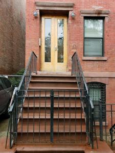 eine Treppe, die zu einer Tür in einem Backsteingebäude führt in der Unterkunft The Harlem Cascades in New York