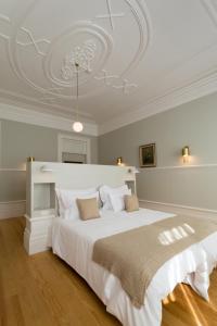 a bedroom with a large white bed with a ceiling at Original Douro Hotel in Peso da Régua