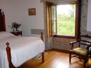 a bedroom with a bed and a window and a chair at Quinta da Picaria in Santo Tirso