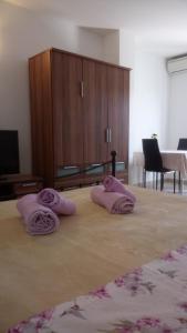 2 serviettes roses assises au-dessus d'un lit dans l'établissement Studio Apartment Ivo, à Cres