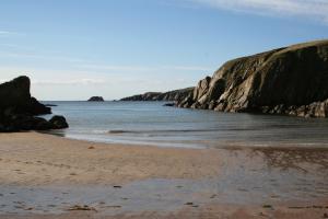 a sandy beach with rocks in the water at Tamara Apartment in Sandwick