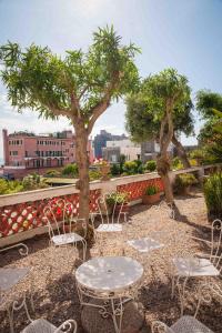 un patio avec des tables, des chaises et des arbres dans l'établissement Hotel Villa Panoramica, à Ischia