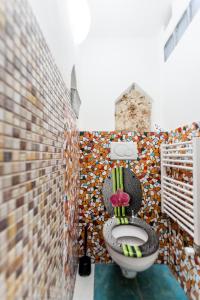 a bathroom with a toilet with a mosaic wall at Dům Pod Věží in Mikulov