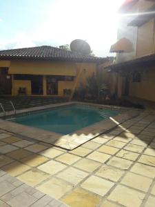 uma piscina em frente a uma casa em Condomínio Pousada Amarela 100 metros da Praia em Iguaba Grande