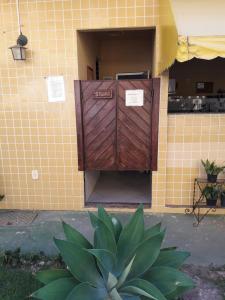 une porte en bois sur le côté du bâtiment dans l'établissement Condomínio Pousada Amarela 100 metros da Praia, à Iguaba Grande