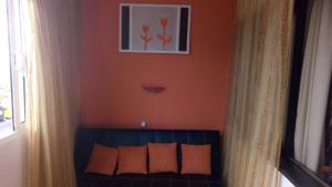 マシコにあるSunny flat In Machico cityのオレンジ色の壁のベッドルーム1室、ベッド1台(オレンジ色の枕付)